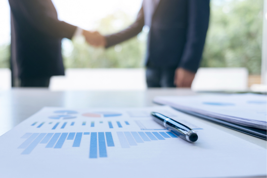 Dois executivos apertando a mão, simbolizando confiança, alinhamento e parceria no ambiente corporativo.